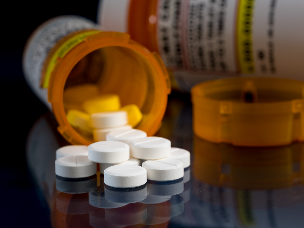 Image of pill bottle tipped over with white pills scattered on table