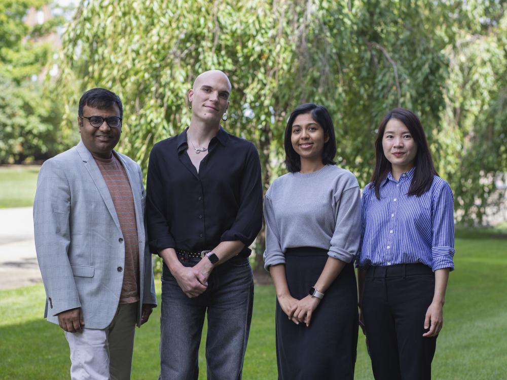 four people in business attire with greenery in background