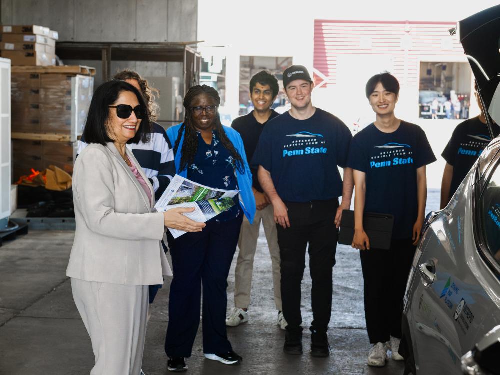 Neeli Bendapudi stands near a car with other administrators and students 