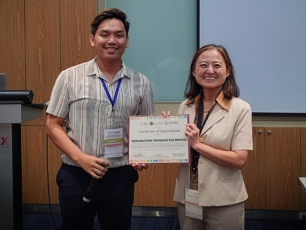 Chingwen Cheng at right accepts a certificate from a leader of the Association of Pacific Rim University Sustainable Cities and Landscapes at left.