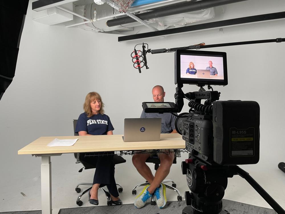 Two faculty experts sit at a desk while being recorded on film