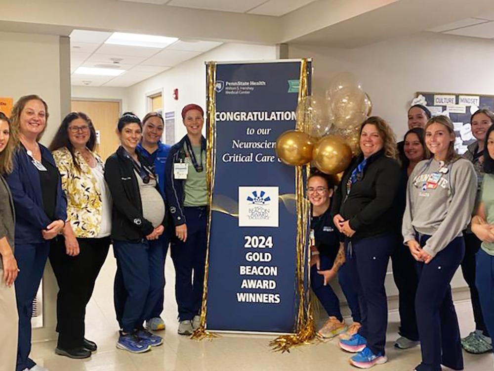 A group of people pose for a photo with a sign touting "2024 Gold Beacon Award Winners."