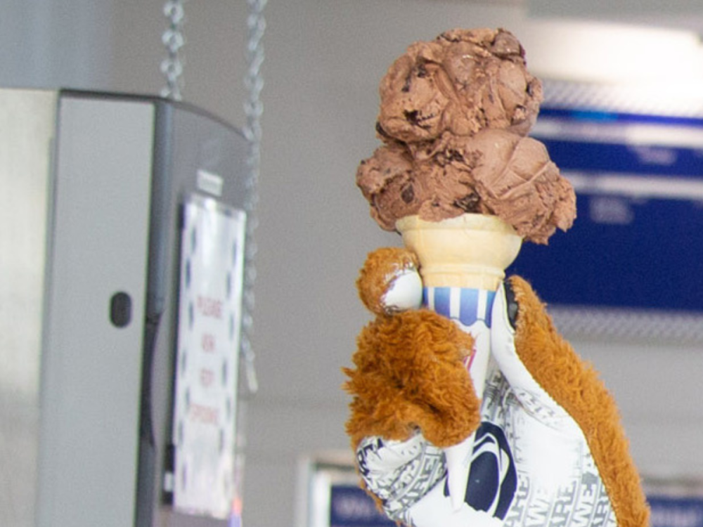 The hand of the Nittany Lion mascot holds up a scoop of ice cream