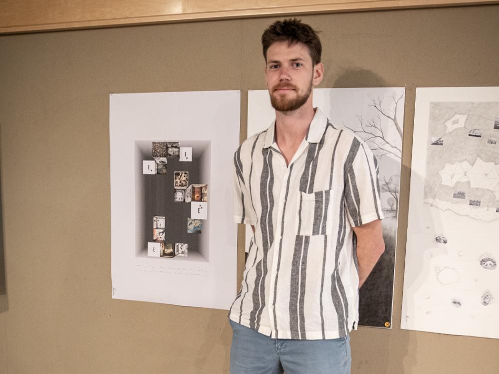 Josh Conway stands to the right of the poster he designed. 