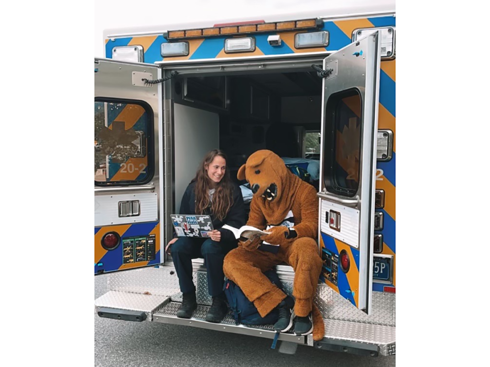 Penn State student Alyssa Fedorshak sits in an ambulance with the Nittany Lion.