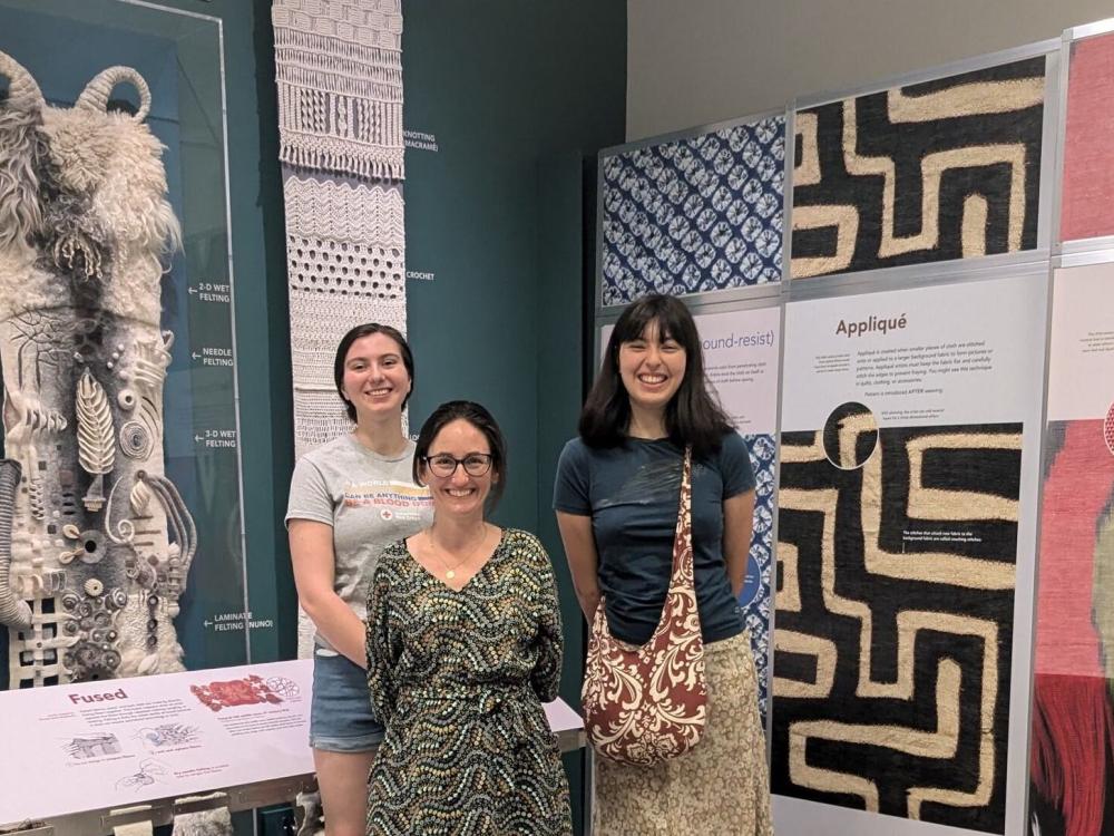 Three women in front of textile museum exhibition