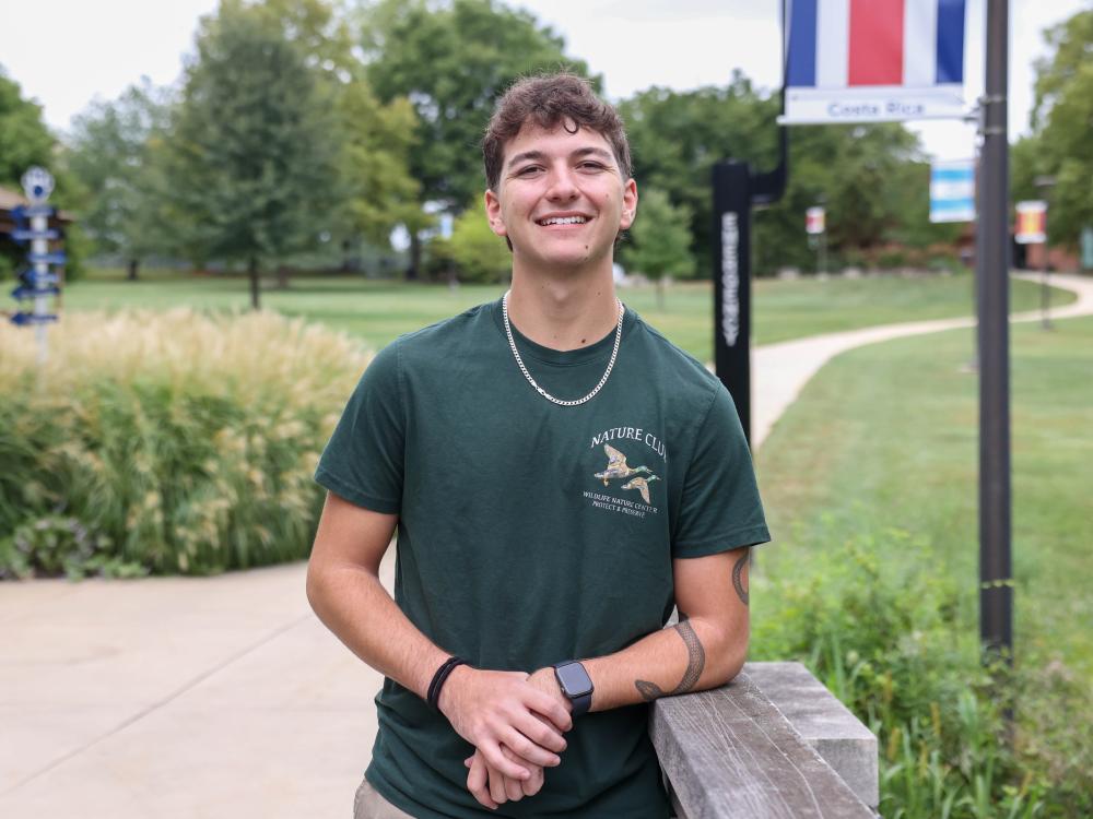 A male student stands on a sidewalk at Penn State Brandywine.