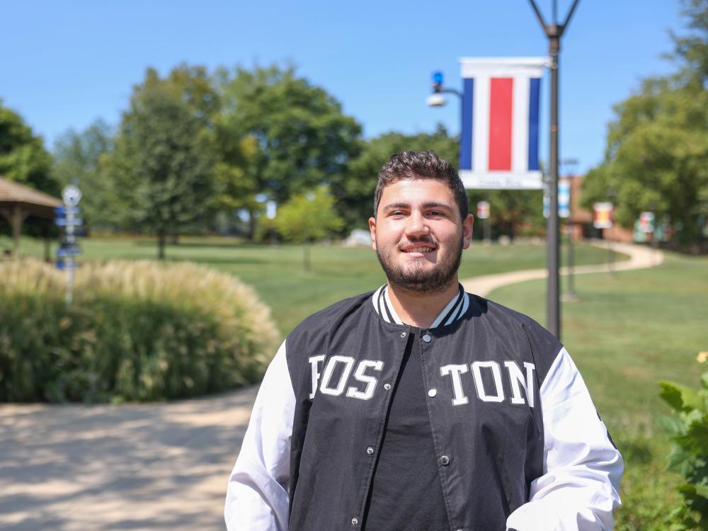 A male student stands on a campus sidewalk at Penn State Brandywine.