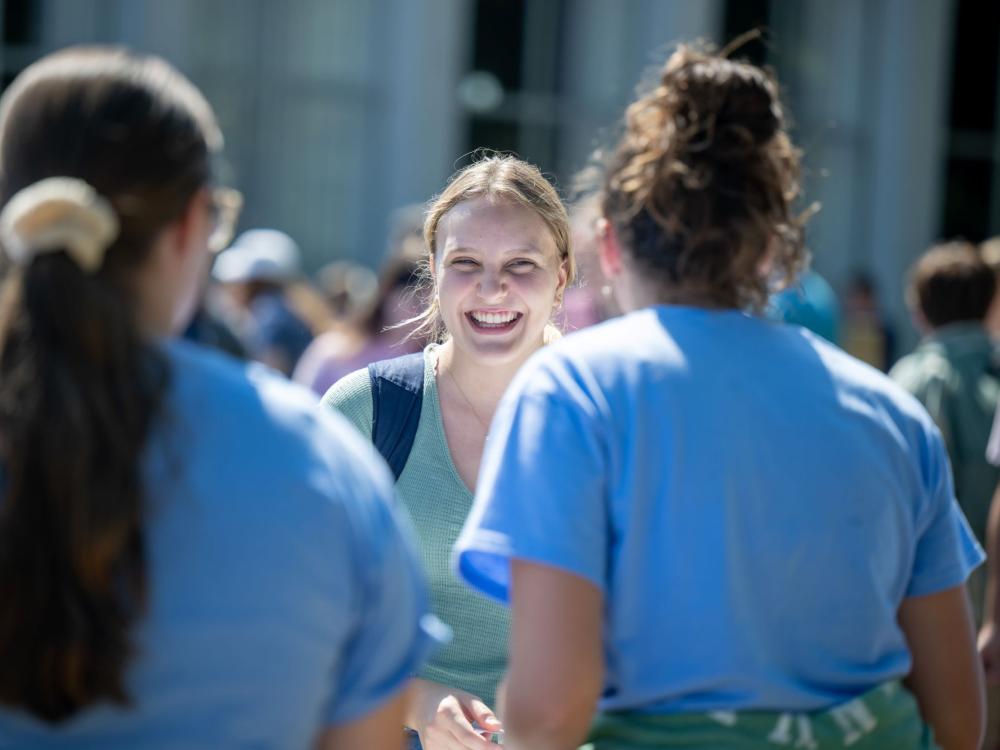 A female student smiles while talking to two others at Penn State Behrend's Discovery Fair.