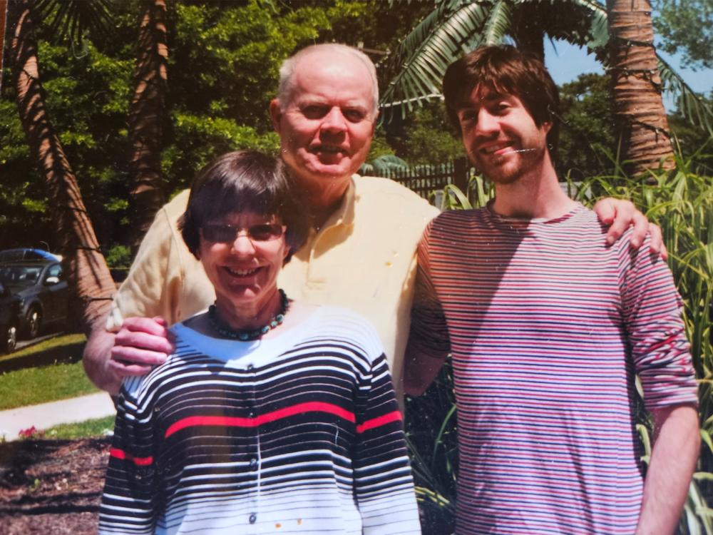 Three individuals pose for an outdoor portrait. 