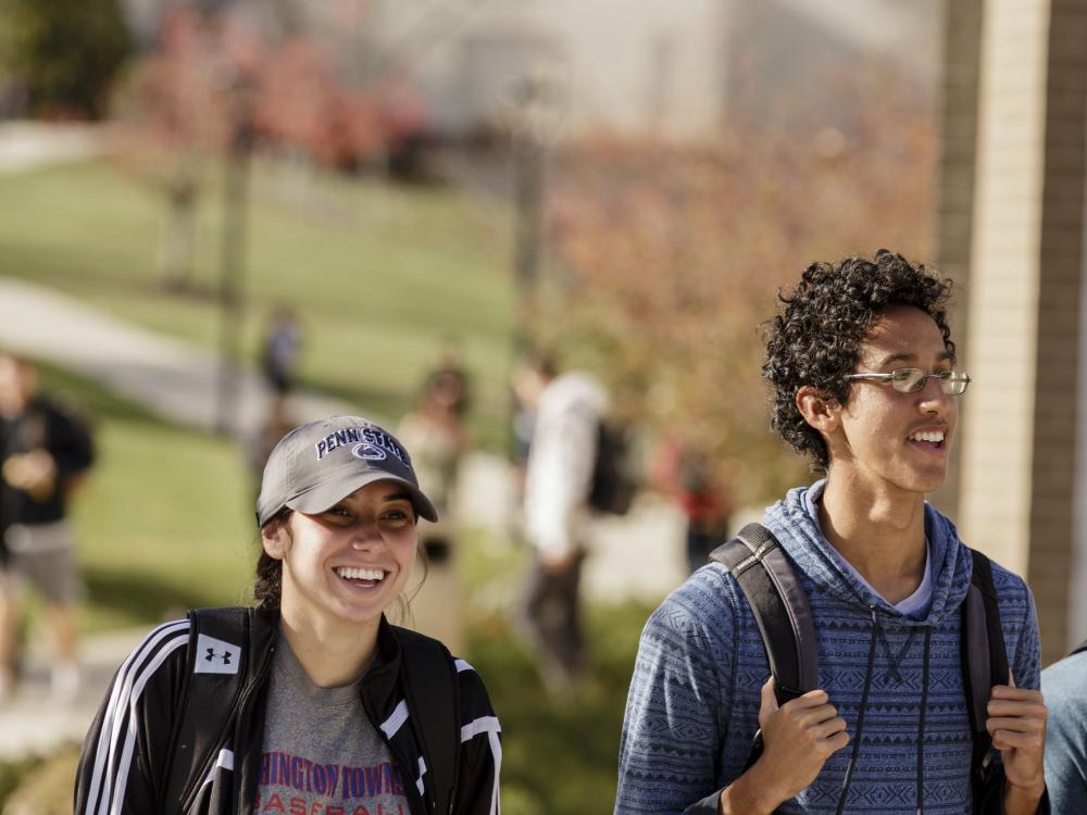Two smiling students walk across Penn State Berks campus