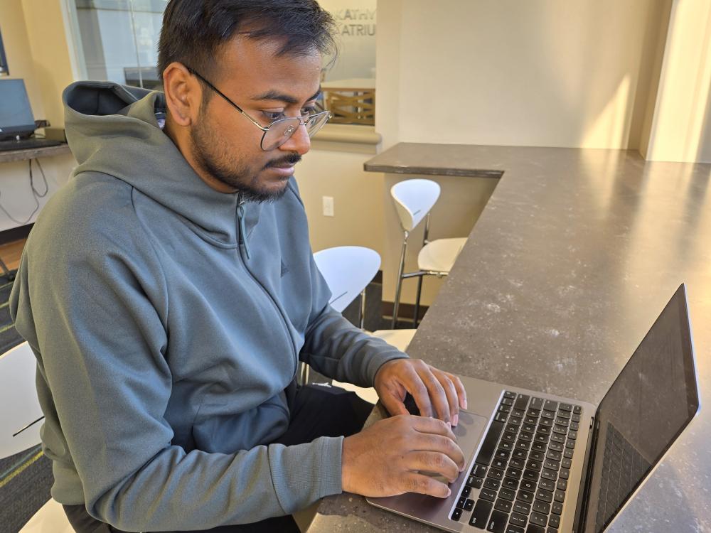 A student researcher works on his laptop