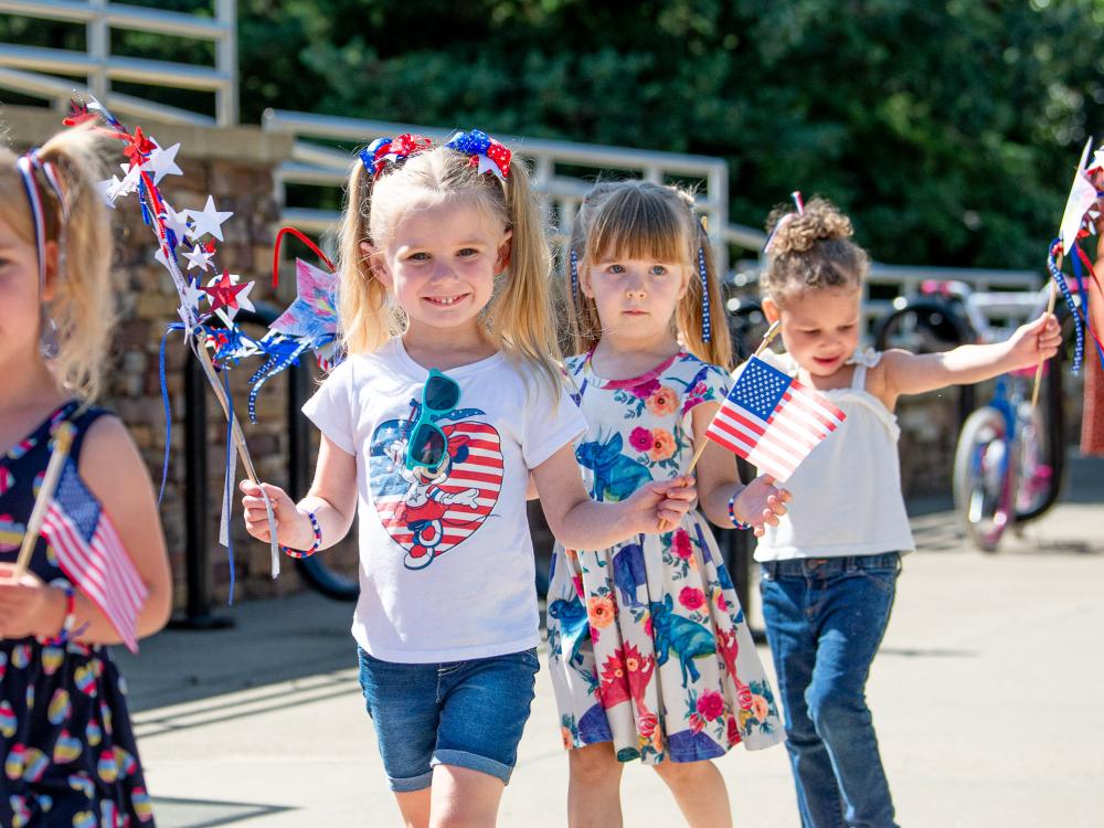 Smiling children outside a learning center take part in a parade