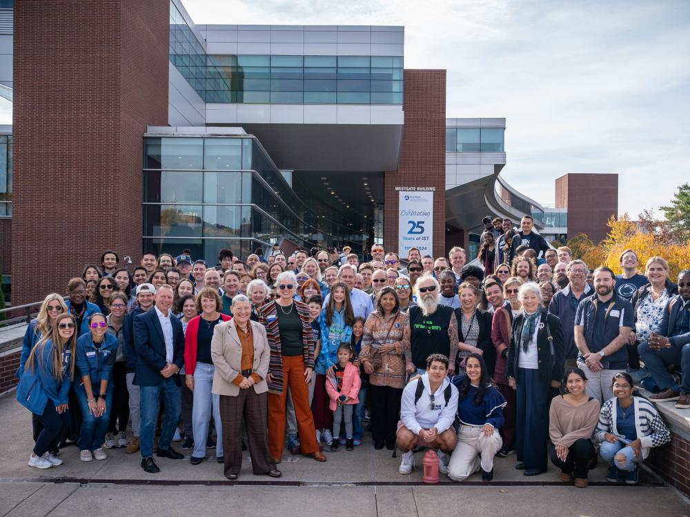 large group of people gather in front of campus building