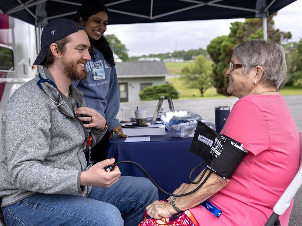 A medical student gives a woman a blood pressure screening.