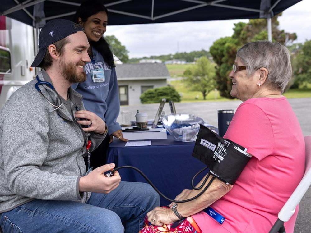 A medical student gives a woman a blood pressure screening.