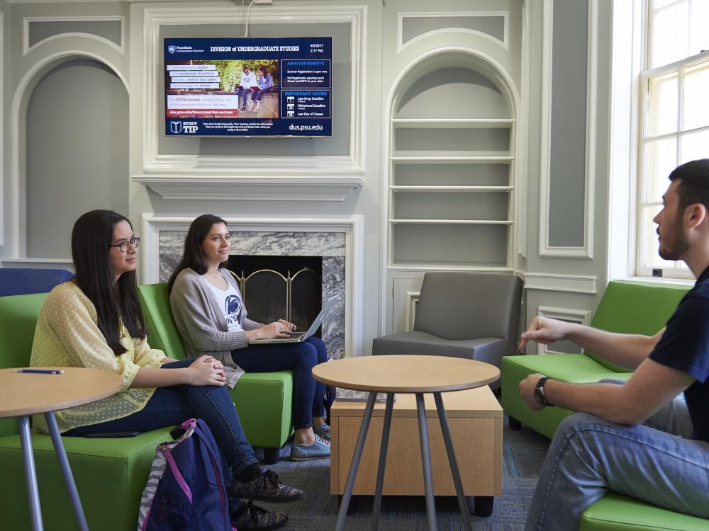 Three students talking in Grange Building lobby