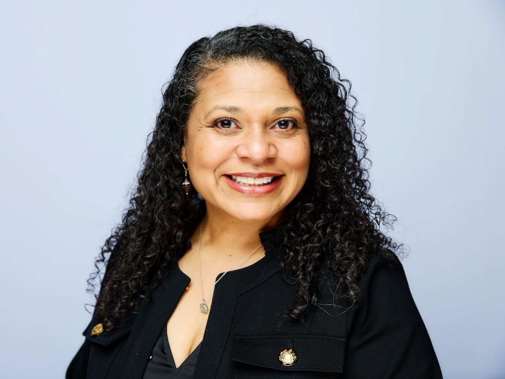 headshot of person with gray curly hair in business attire