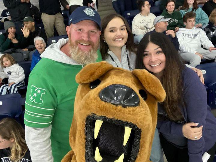 A family smile for a selfie with the Nittany Lion at a hockey game