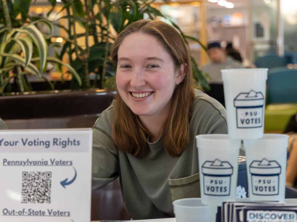 one female student sitting at a table smiling at the camera