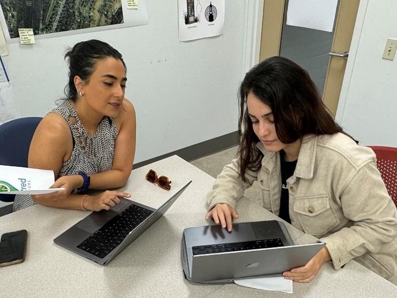 Two people work on a laptop together.