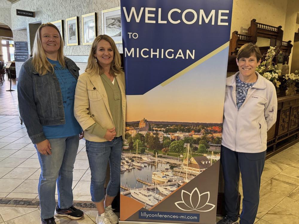 Angela Pettitt, Tammy Divens, and Kathy Shaffer pose with a Lilly Conference sign