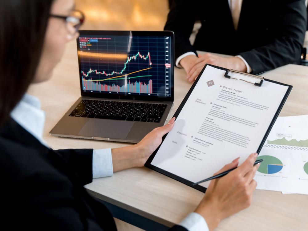 person with glasses reviews resume on clipboard