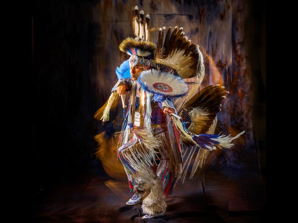 Supaman wearing beautiful traditional Native American clothing and dancing