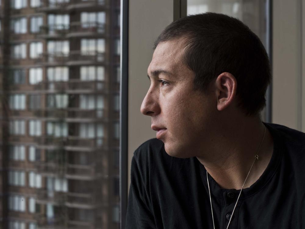 Profile photo of Tommy Orange staring out of a window.
