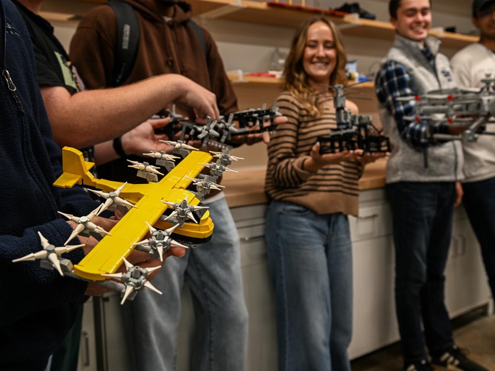 A group of students hold LEGO models of planes in a lab setting. 