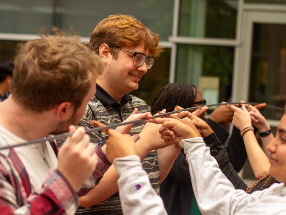 IDEA Ambassadors participate in a community building activity holding a bar in the air