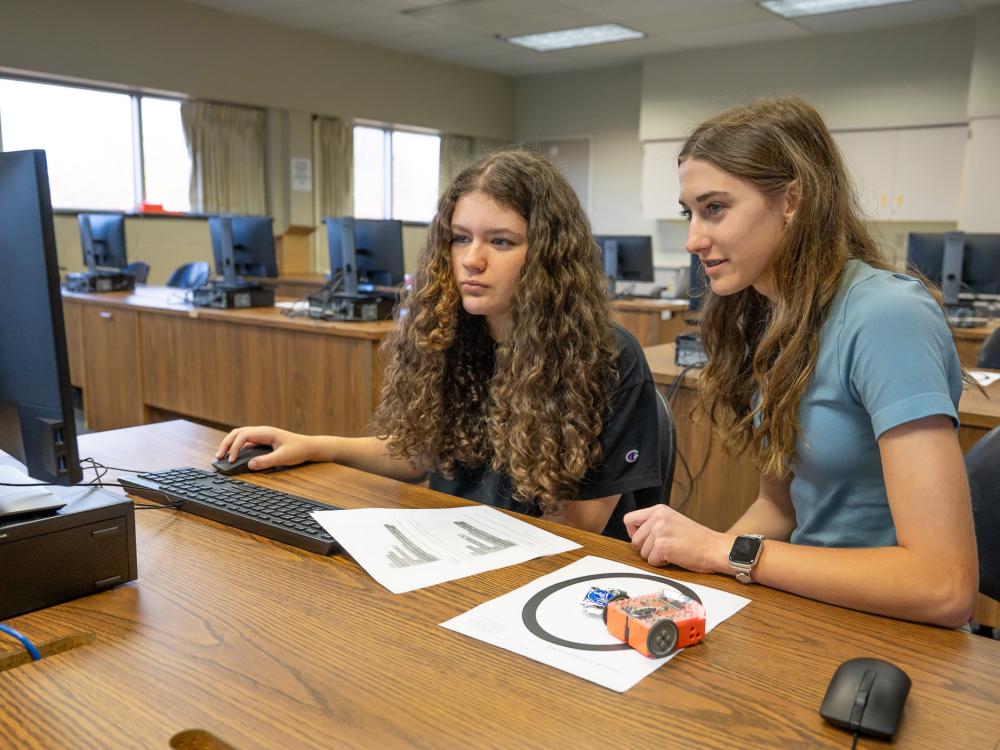 Two students work on coding a robot