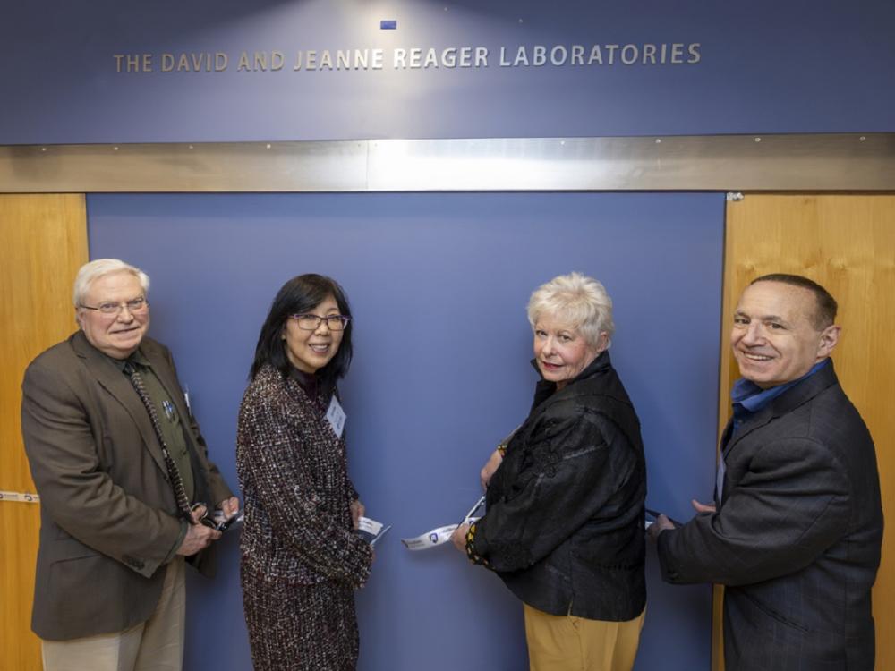 Four people cut the ribbon on a plaque to name research laboratories