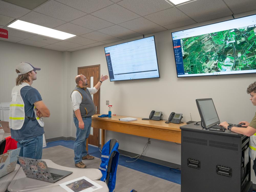 Student in a classroom use software displayed on a large screen.