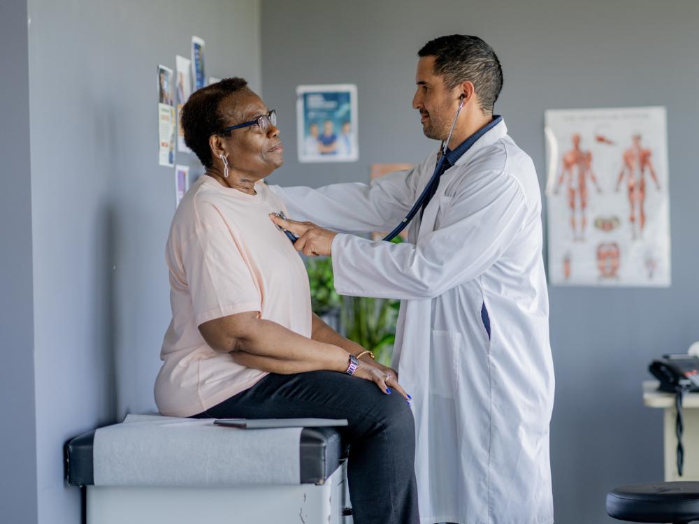 Older person sits up on an exam table during a routine health check-up