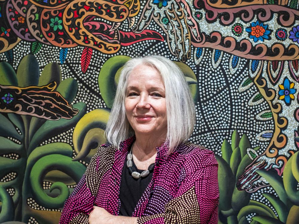 Women with chin-length gray hair in front of multicolored wall