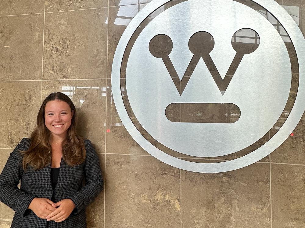 Sabrina Knox stands next to the Westinghouse logo inside a Westinghouse building in Pittsburgh.