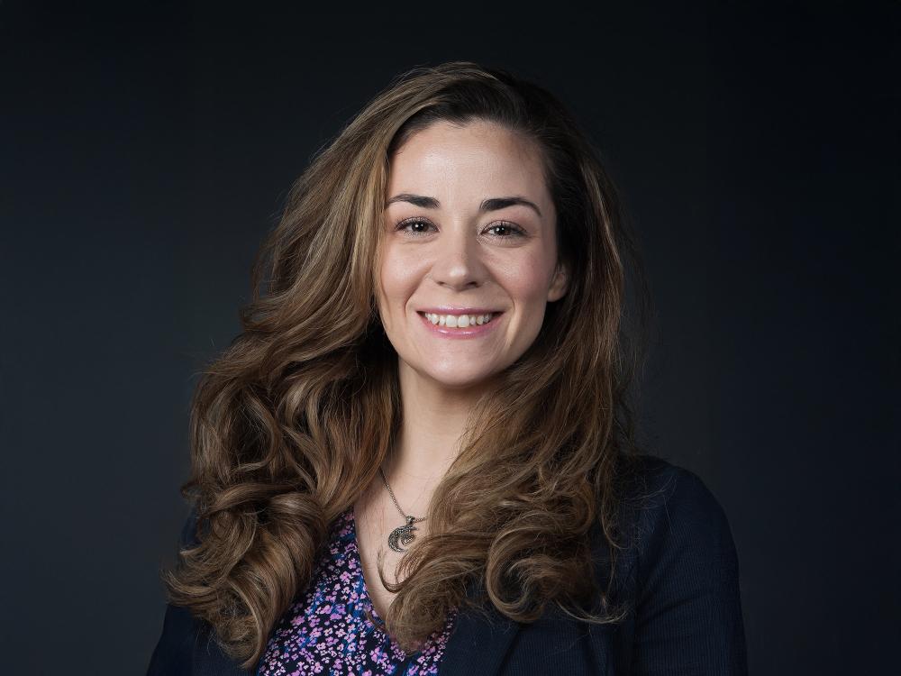 Lauren Noland poses for her official headshot against a black background.