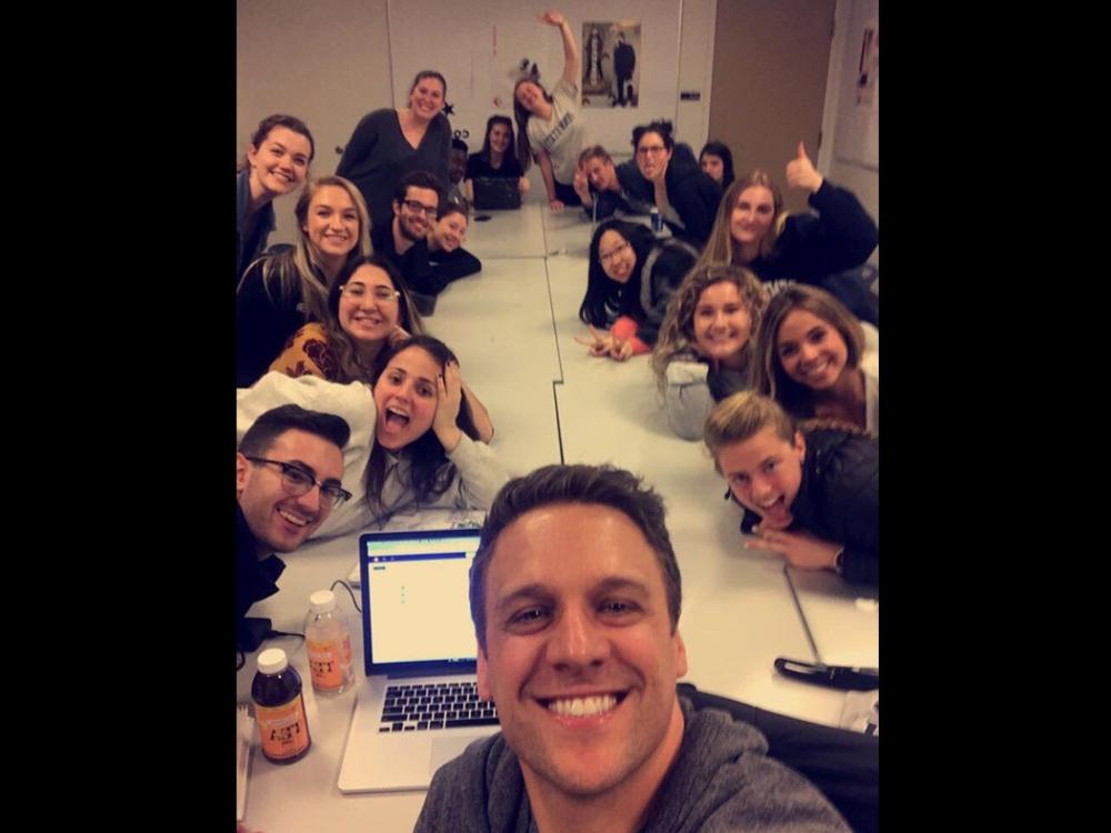 Ryan Russell taking a selfie with his students around a long table. 