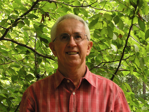 Man in front of bushes and a tree