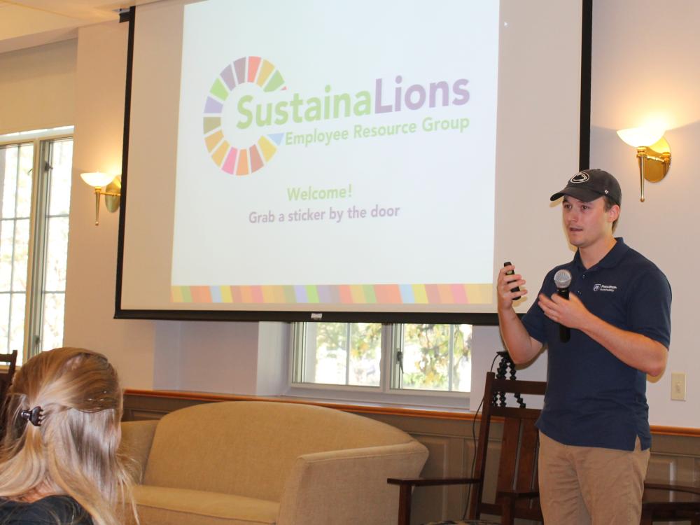 A person stands next to a screen during a SustainaLions presentation.