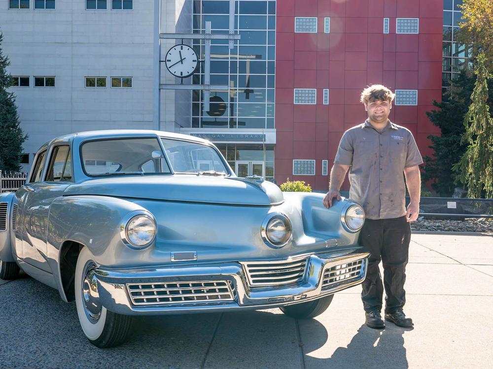 Ty Tucker stands with a restored vintage car