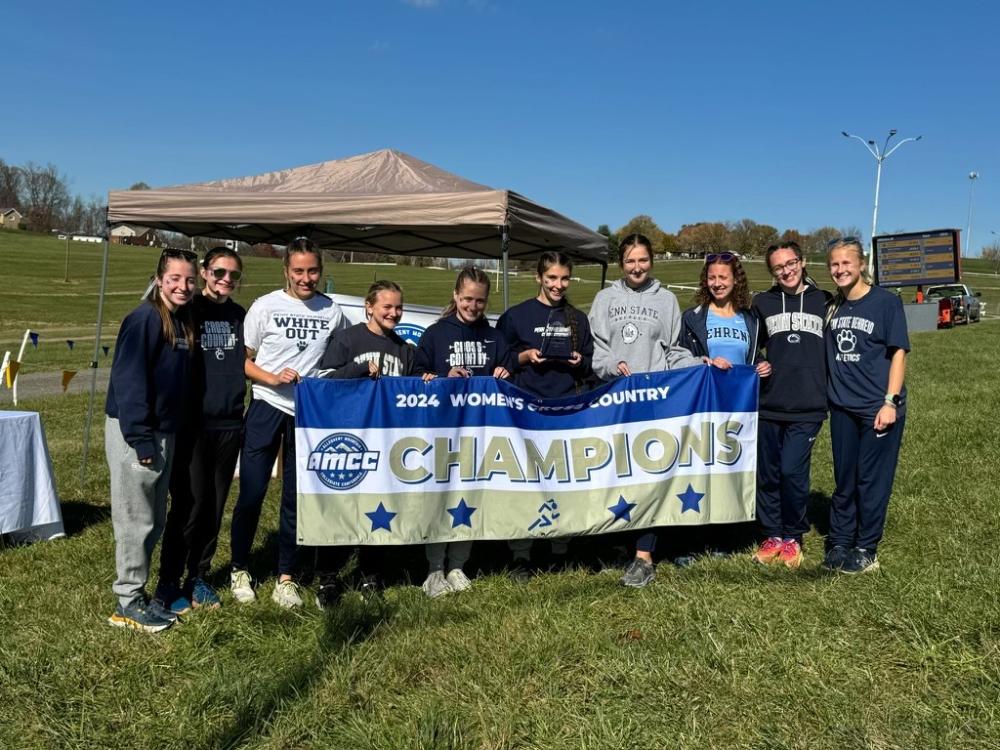 The Penn State Behrend women's cross country team poses with the AMCC championship banner.