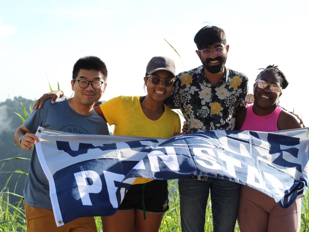 Four students with a Penn State flag in a field