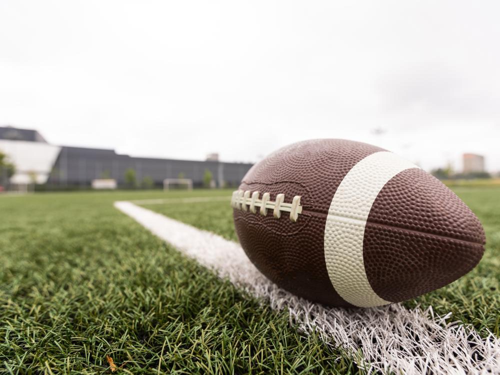 a football in the foreground rests on a football field