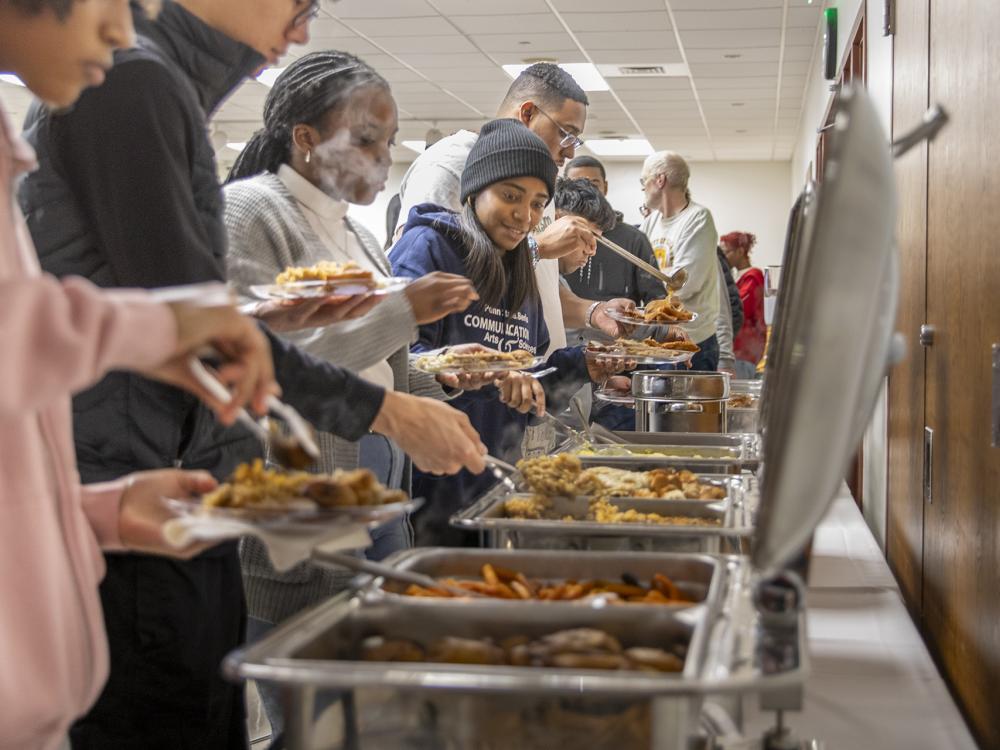 Students serve themselves food from chafing dishes.