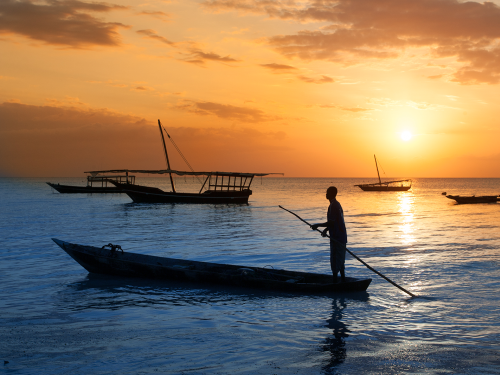 A person in a boat off the Tanzanian coast at sunset.