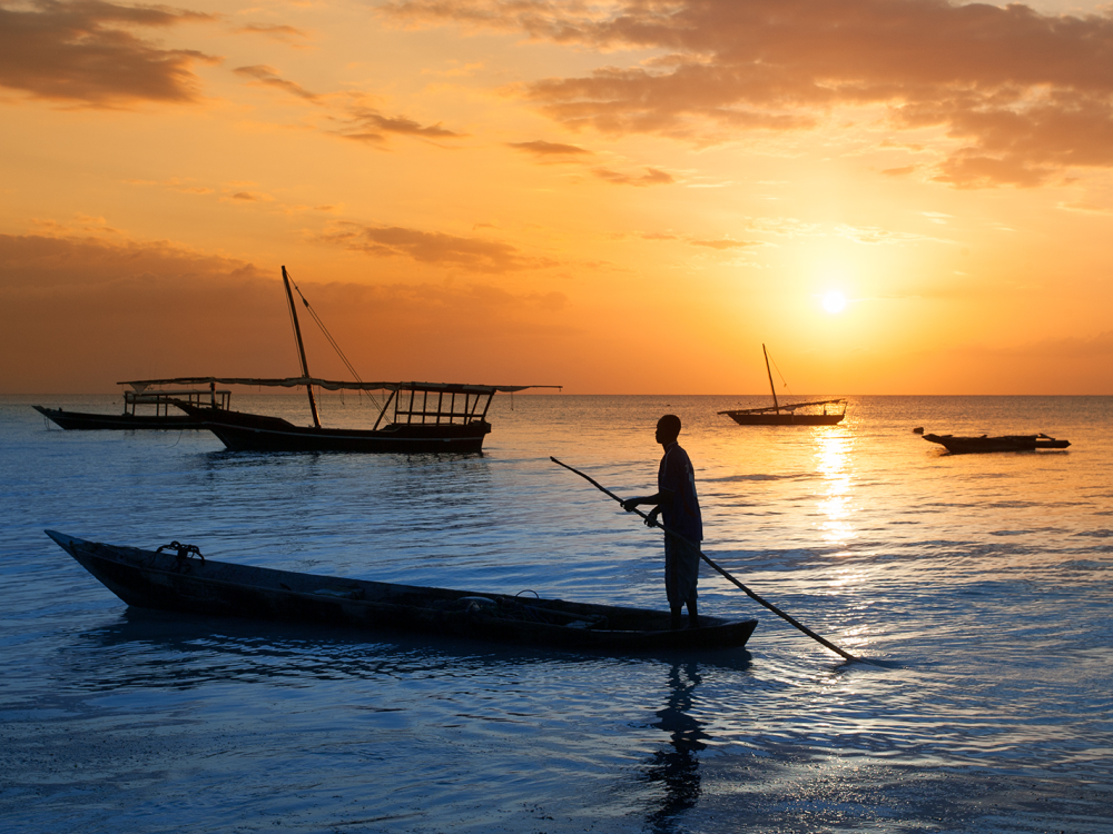 A person in a boat off the Tanzanian coast at sunset.