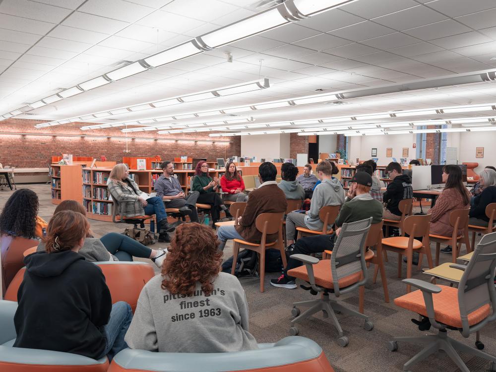 Students and guests listen to faculty speaking panel in library