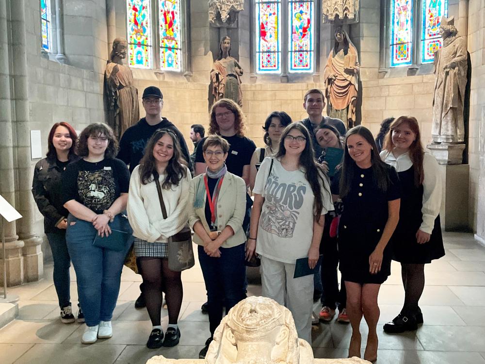 students posing in a two-row, standing formation inside The Cloisters museum